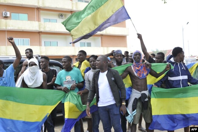 People holding Gabon national flags celebrate in Libreville on August 30, 2023. A group of Gabonese military officers appeared on television saying "all the institutions of the republic" had been dissolved, the election results canceled and the borders closed. (Photo by AFP)