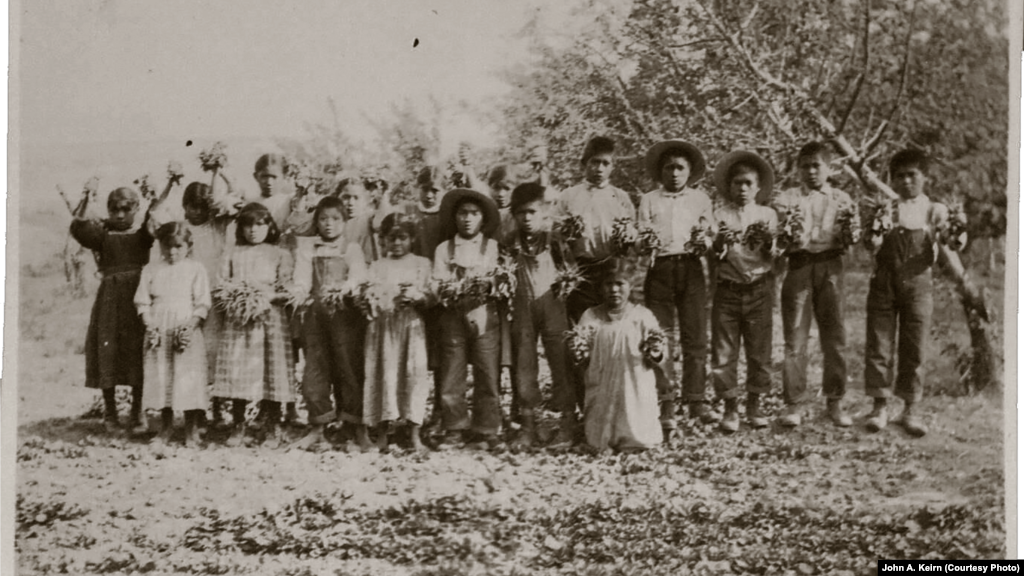 In this undated photo taken by John A. Keirn, students pose holding what appear to be radishes gathered at the school farm.