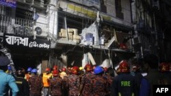 ঢাকায় বিস্ফোরণের পর একটি ভবনের বাইরে অগ্নিনির্বাপক ও জরুরী কর্মীরা দাঁড়িয়ে আছেন। (ছবি রেহমান আসাদ/এএফপি)