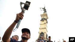 Douglas Guzman takes video with his smartphone at Liberty Plaza in San Salvador, June 24, 2023. Guzmán is part of a network of social media personalities acting as a megaphone for, and cashing in on, El Salvador President Nayib Bukele's message. 