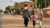 Women and a boy walk along a street in Khartoum on April 18, 2023.