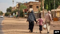 Women and a boy walk along a street in Khartoum on April 18, 2023.