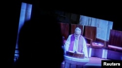 Un periodista observa una transmisión televisiva en vivo mientras el sacerdote Josu López Villalba, víctima de abuso sexual, habla durante una misa en Bilbao, España, 24 de marzo de 2023. 