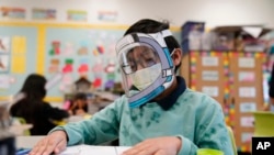 FILE - A student wears a mask and face shield in a fourth-grade class amid the COVID-19 pandemic at Washington Elementary School on Jan. 12, 2022, in Lynwood, California.