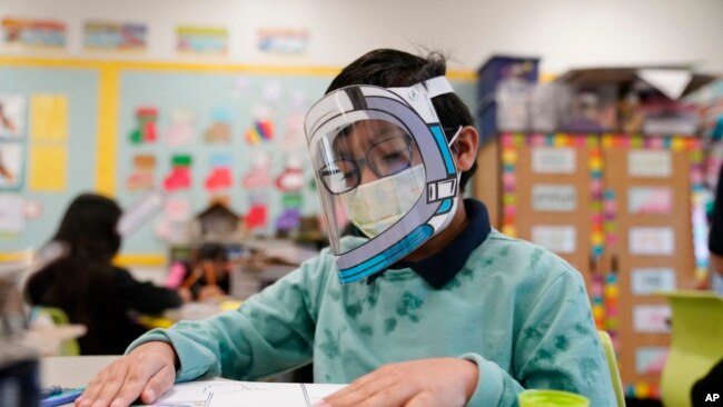 FILE - A student wears a mask and face shield in a fourth grade class amid the COVID-19 pandemic at Washington Elementary School on Jan. 12, 2022, in Lynwood, Calif.