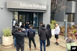 Seorang petugas Bank Silicon Valley berbicara dengan para nasabah yang berdiri di luar kantor SVB di Santa Clara, California, Jumat, 10 Maret 2023. (Foto: Jeff Chiu/AP Photo)