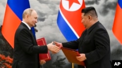 Russian President Vladimir Putin, left, and North Korea's leader Kim Jong Un exchange documents during a signing ceremony of the new partnership in Pyongyang, North Korea, June 19, 2024.