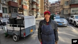 Duan Shuangzhu, 68, a waste collector who moved to Beijing in late 1990s from a small village in central China's Shanxi, stands near a rubbish cart while working in Beijing on March 1, 2024.
