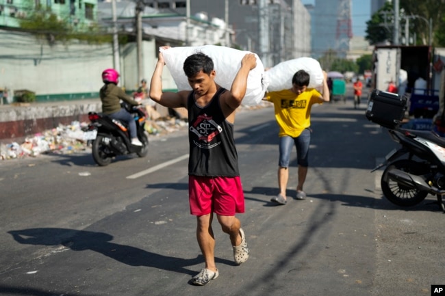 FILE - Men deliver sacks of ice cubes as demand remains high due to hot temperatures in Quezon city, Philippines on April 24, 2024. (AP Photo/Aaron Favila, File)