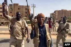 Fighters wave assault rifles as they cross a street in the East Nile district of greater Khartoum, in image grab taken from handout video footage released by the Sudanese paramilitary Rapid Support Forces on April 23, 2023.