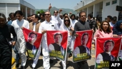 FILE - Parliamentarians of the Pakistan Tehreek-e-Insaf (PTI) party carry posters of jailed former prime minister Imran Khan, during a protest outside the Parliament house in Islamabad on July 18, 2024. 