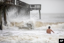 A surfer takes advantage of the large surf as Tropical Storm Debby approaches in Isle of Palms, South Carolina, Aug. 7, 2024.