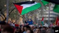 A boy waves a Palestinian flag as demonstrators march during a protest in support of Palestinians and calling for an immediate cease-fire in Gaza, in Barcelona, Spain, Jan. 20, 2024.