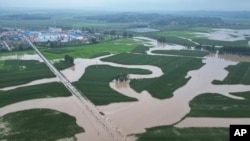 In this photo released by Xinhua News Agency, floodwaters course through fields and roads in Kaiyuan Town of Shulan in northeastern China's Jilin province, Aug. 4, 2023.