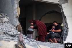 A Palestinian family gathers around a makeshift wood stove in a damaged building in Khan Yunis in the southern Gaza Strip on July 4, 2024.