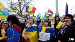 FILE - Participants wave European Union, Ukrainian and EU member flags during a rally for Ukraine on the second anniversary of Russia's invasion, in Paris, Feb. 24, 2024.