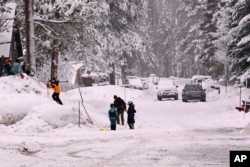 Children play on the snow off Donner Pass Road, March 1, 2024, in Truckee, California. The most powerful Pacific storm of the season was forecast to bring up to 10 feet of snow into the Sierra Nevada by the weekend.