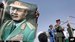 FILE - A man holds a poster showing former Sudanese President Jaafar al-Nimeiri, who became Sudan's president in 1969 and was overthrown in a bloodless coup in 1985, during his military funeral in Omdurman, Khartoum, May 31, 2009.