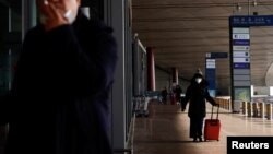 FILE - A traveler walks with a suitcase outside at a terminal hall, during the annual Spring Festival travel rush ahead of the Chinese Lunar New Year, in Beijing Capital International Airport, Beijing, China Jan. 18, 2023. 