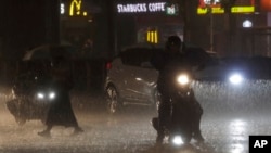 People walk and drive under heavy rain as the Typhoon Haikui approaches the country, in Taipei, Sept. 2, 2023.