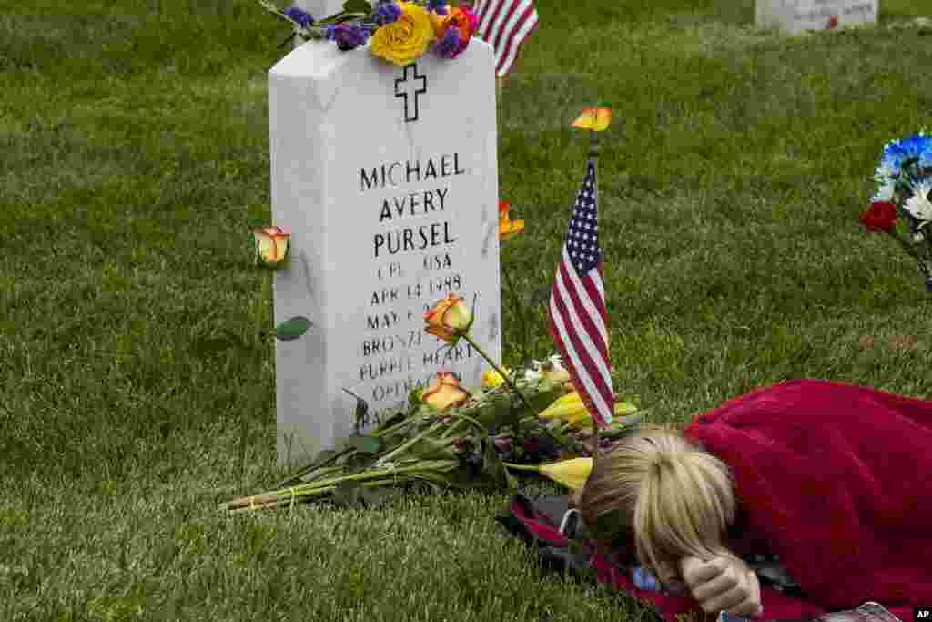 Avery Carlin of Arlington, rests by the headstone of her uncle U.S. Army Cpl. Michael Avery Pursel as she visits Section 60 at Arlington National Cemetery with her family on Memorial Day, in Arlington, Virginia.