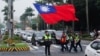 台湾警察护送一名举着台湾旗帜的男子走过台北街头。（2024年5月24日）
