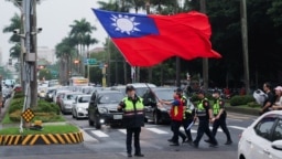 台湾警察护送一名举着台湾旗帜的男子走过台北街头。（2024年5月24日）