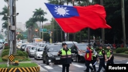 台灣警察護送一名舉著台灣旗幟的男子走過台北街頭。（2024年5月24日）