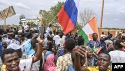 FILE - Supporters of Niger's coup leaders hold a Russian flag as they demonstrate in Niamey on Aug. 11, 2023. Nigerien state media reported on April 11, 2024, that Russian military trainers had arrived in the country.