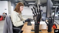 FILE - Olena Pozniakova, 28, a quality assurance engineer, tests the app for bionic prostheses at the Esper Bionics office in Kyiv, Ukraine, Oct. 31, 2023. 