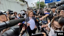 香港民主派初選47人案其中一名獲判無罪的被告，大律師劉偉聰手持法庭裁決判詞，被大批傳媒包圍採訪。(美國之音照片)