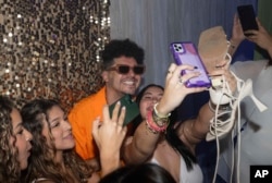 Dr. Pedro Juan Vázquez, better known by his stage name PJ Sin Suela, poses for group selfies at a high school prom in Camuy, Puerto Rico, Thursday, June 6, 2024. (AP Photo/Alejandro Granadillo)