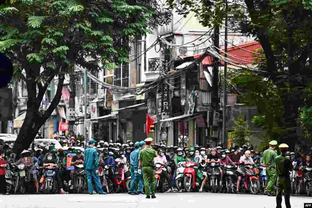 People wait as the road is blocked for the convoy carrying U.S. President Joe Biden in Hanoi following a two-day visit to Vietnam.