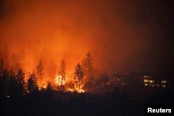 The McDougall Creek wildfire burns next to houses in the Okanagan community of West Kelowna, British Columbia, Canada, on Aug. 19, 2023.