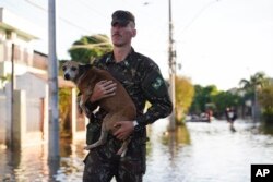 A soldier evacuates a dog from a flooded area after heavy rain in Canoas, Rio Grande do Sul state, Brazil, May 9, 2024.