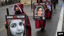 Demonstrators hold placards reading "Women, Life, Freedom" as they demonstrate against the persecution of women in Iran, on Whitehall in central London on March 8, 2023.