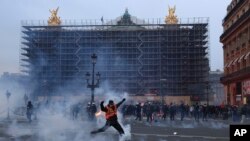 Un manifestante lanza un bote de gas lacrimógeno frente a la Ópera al final de una manifestación en París, el jueves 23 de marzo de 2023.