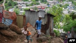 Des riverains se promènent dans le bidonville "Talus 2" sur le versant de Majicavo, près de Koungou, sur le territoire français de l'océan Indien de Mayotte, le 19 février 2023.