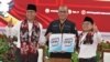 Anies Baswedan (kiri), Ketua Komisi Pemilihan Umum (KPU) Hasyim Asy'ari (tengah) dan Muhaimin Iskandar (kanan) menunjukkan dokumen pendaftaran sebagai calon presiden dan wakil presiden dalam pilpres 2024 mendatang, Jakarta, Kamis, 19 Oktober 2023. (Foto: Indra Yoga/VOA)