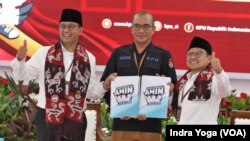 Anies Baswedan (kiri), Ketua Komisi Pemilihan Umum (KPU) Hasyim Asy'ari (tengah) dan Muhaimin Iskandar (kanan) menunjukkan dokumen pendaftaran sebagai calon presiden dan wakil presiden dalam pilpres 2024 mendatang, Jakarta, Kamis, 19 Oktober 2023. (Foto: Indra Yoga/VOA)