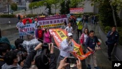 FILE - Protesters walk within a cordon line wearing number tags during a rally in Hong Kong, March 26, 2023.