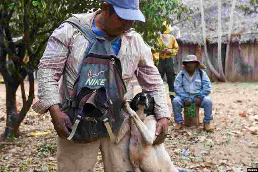 A community member hugs his dog before being evacuated by members of the Armed Forces from the affected areas, while supporting the fight against wildfires in Nuflo de Chavez Province, Bolivia, Aug. 25, 2024.