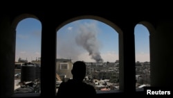 Seorang pria Palestina menyaksikan asap mengepul akibat serangan Israel saat pasukan Israel melancarkan operasi darat dan udara di bagian timur Rafah, selatan Jalur Gaza, 7 Mei 2024. (REUTERS/ Hatem Khaled)