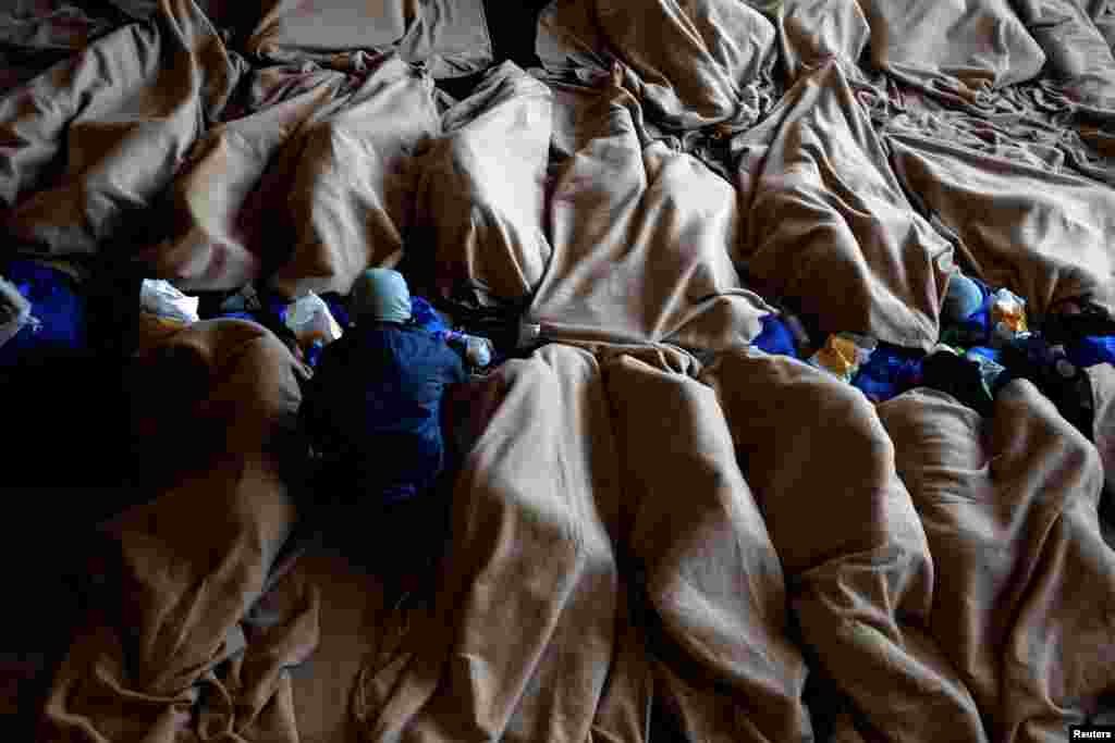 Rescued migrants rest on the Geo Barents rescue ship, operated by Medecins Sans Frontieres (Doctors Without Borders), as the ship makes its way to the Italian port of Bari, in the central Mediterranean Sea, March 25, 2023.