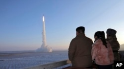 In this undated photo provided, Dec. 18, 2023, by the North Korean government, North Korean leader Kim Jong Un, his daughter and an official watch what it says is an intercontinental ballistic missile launching from an undisclosed location in North Korea.