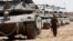 An Israeli soldier walks near tanks parked near the southern Israel-Gaza border, amid the ongoing conflict between Israel and the Palestinian Islamist group Hamas, in Israel, April 28, 2024.