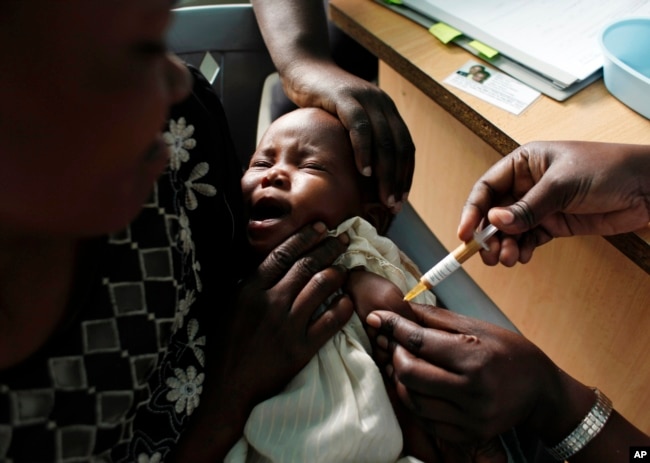 FILE - A mother holds her baby receiving a new malaria vaccine as part of a trial at the Walter Reed Project Research Center in Kombewa in Western Kenya on Oct. 30, 2009. (AP Photo/Karel Prinsloo, File)