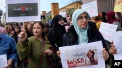 Lebanese teachers hold Arabic placards that read: "Right is not a good deed" and on left, the "Strike of dignity," during a protest outside the Education Ministry, in Beirut, Lebanon, March 6, 2023.