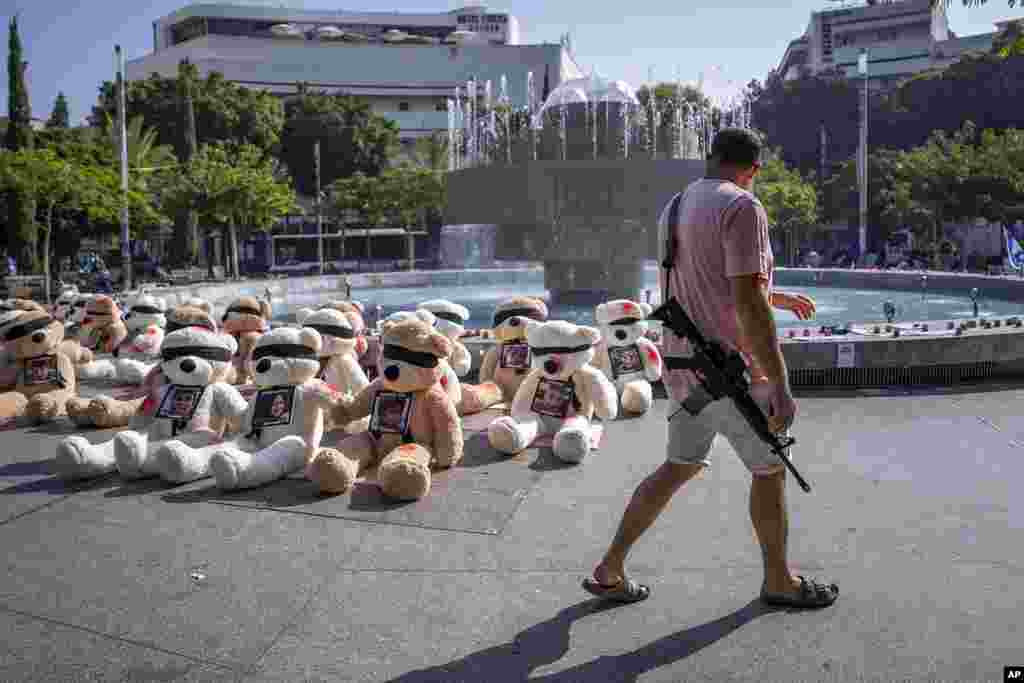 An off-duty Israeli soldier walks by an installation of blindfolded giant teddy bears adorned with photos of Israelis held captive in Gaza, in Tel Aviv, Israel.&nbsp;The installation is meant to draw attention to over 200 people who were abducted by Hamas militants during a bloody and unprecedented October 7 cross-border attack.