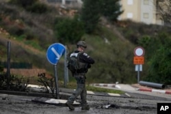 Israeli security forces examine a road hit by a rocket fired from Lebanon, in Kiryat Shmona, northern Israel, Jan. 11, 2024.